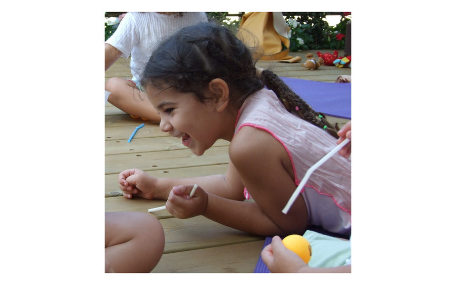 A child smiling during an outdoor Rainbow Yoga activity, from the real photo archive.