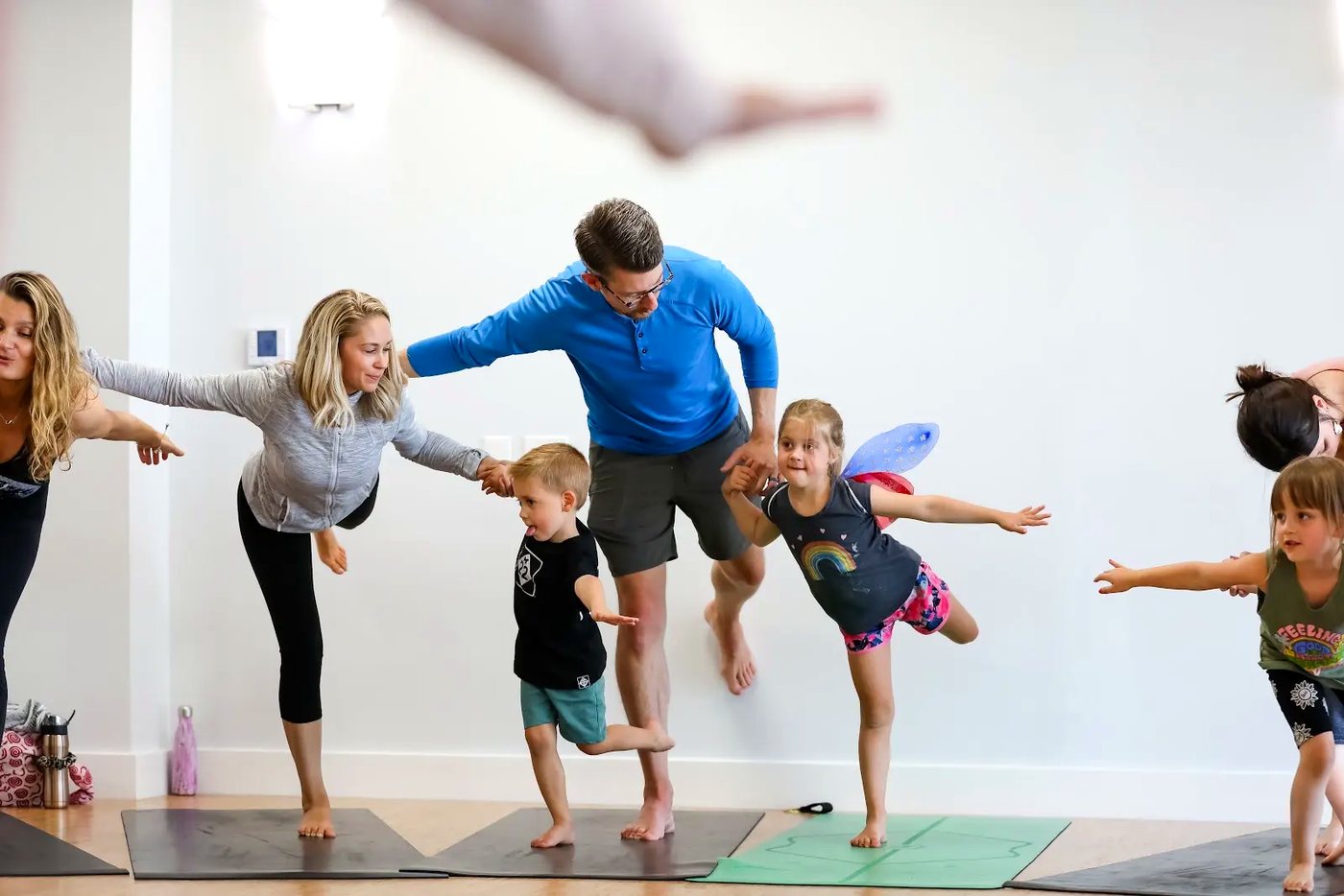 Adults and children making a playful Rainbow Yoga shape