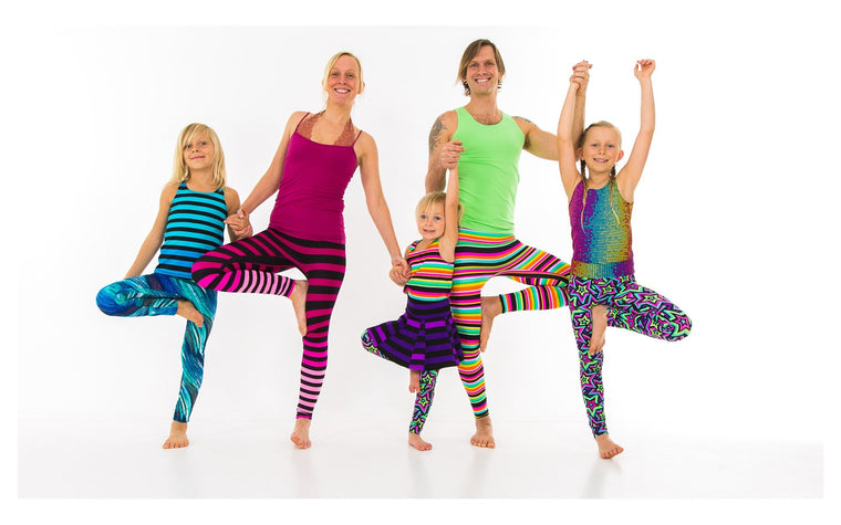 Adults and children exploring a shared standing balance, from the Rainbow Yoga photo archive.
