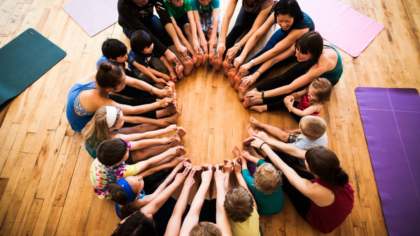 Children and adults sitting together in a Rainbow Yoga circle activity