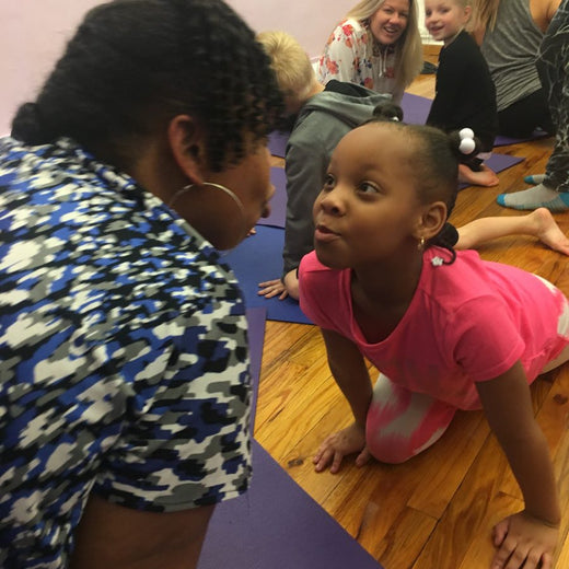 Adults and children sharing a warm Rainbow Yoga family practice
