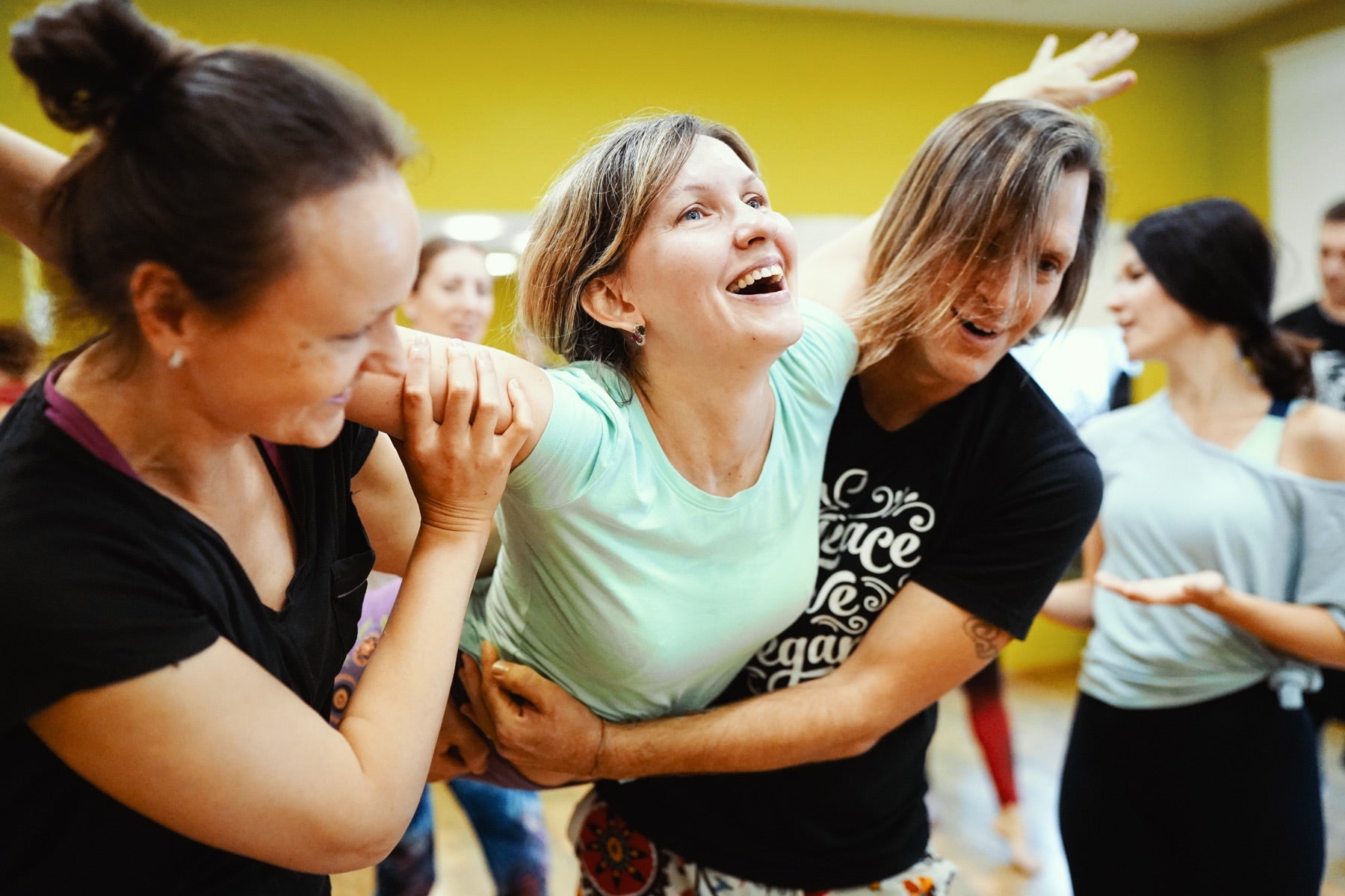 Rainbow Yoga students laughing and supporting each other in partner yoga practice