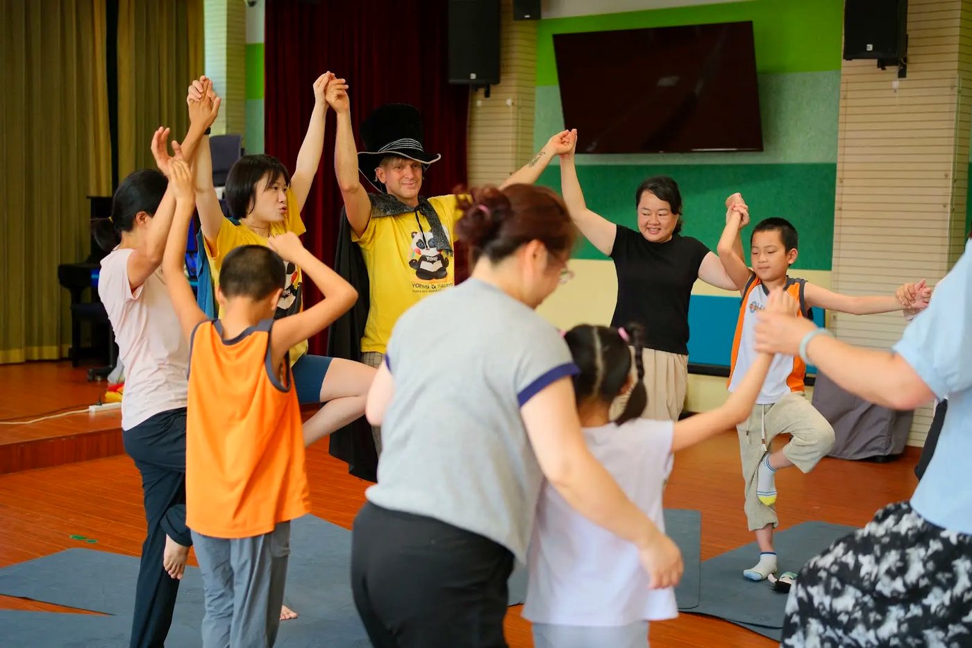 Children and adults moving together in a joyful Rainbow Yoga circle