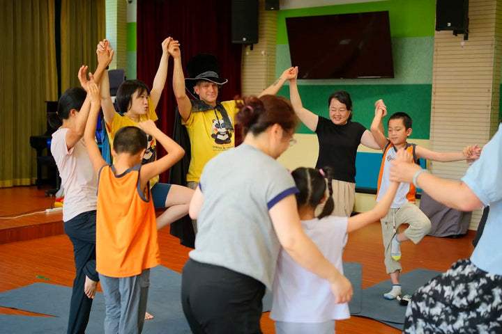 Children and adults moving together in a joyful Rainbow Yoga circle